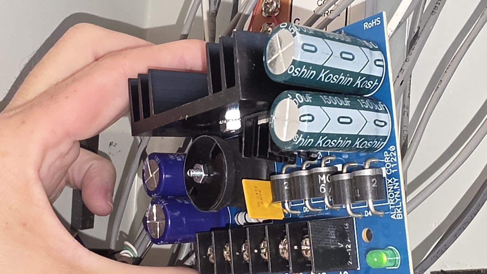 An Altronix supply pulled for testing, Koshin filter capacitors and the AC/battery terminal block.